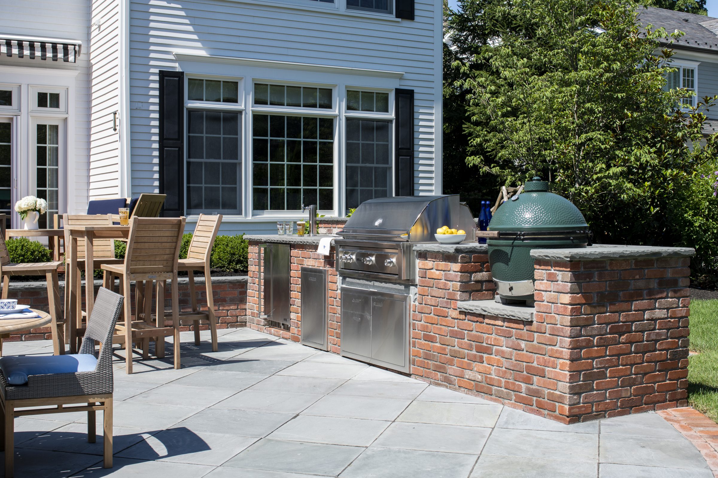 Outdoor kitchen with grill and seating area.