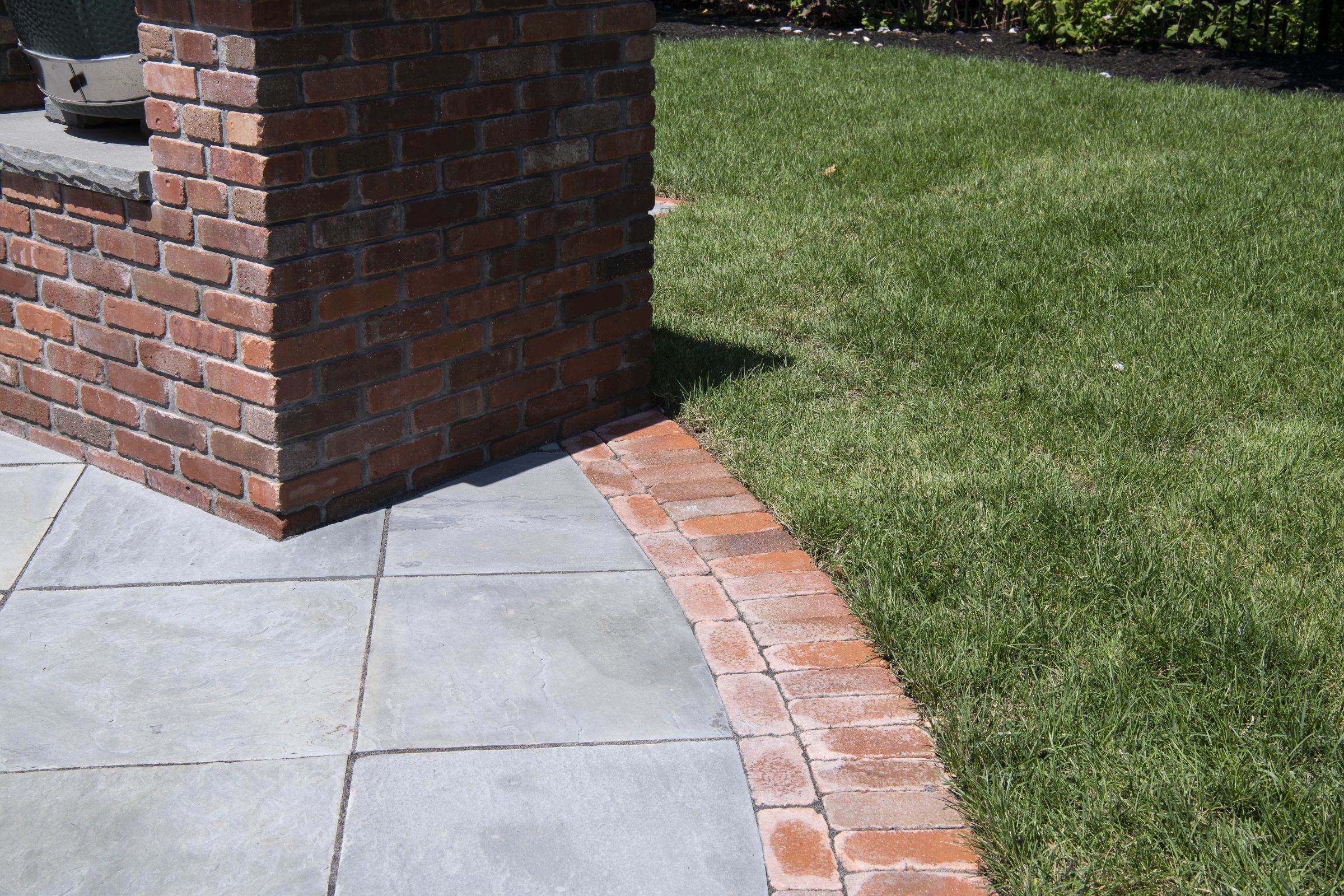 Brick and stone patio corner with grass
