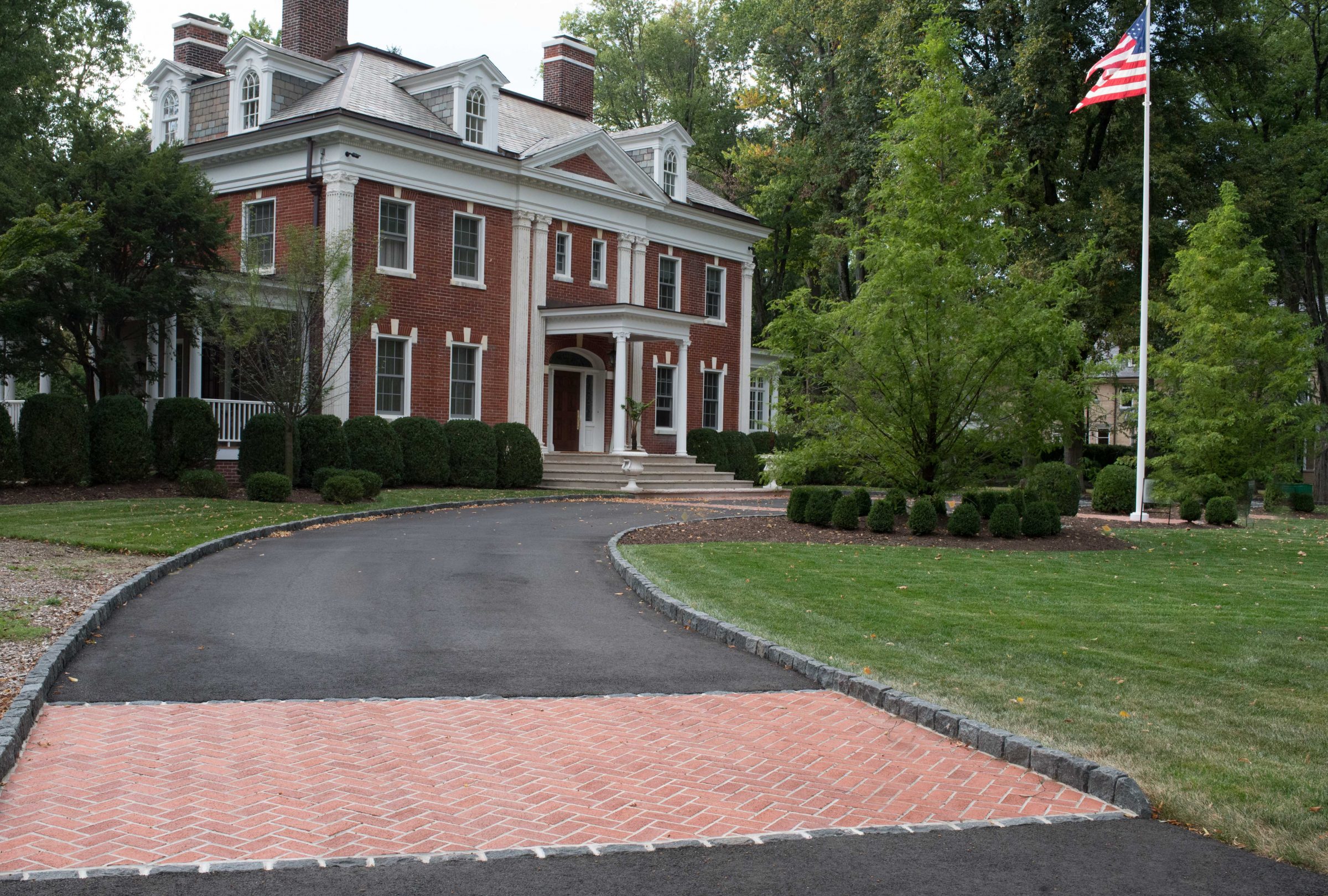 Elegant red brick mansion with driveway and flagpole