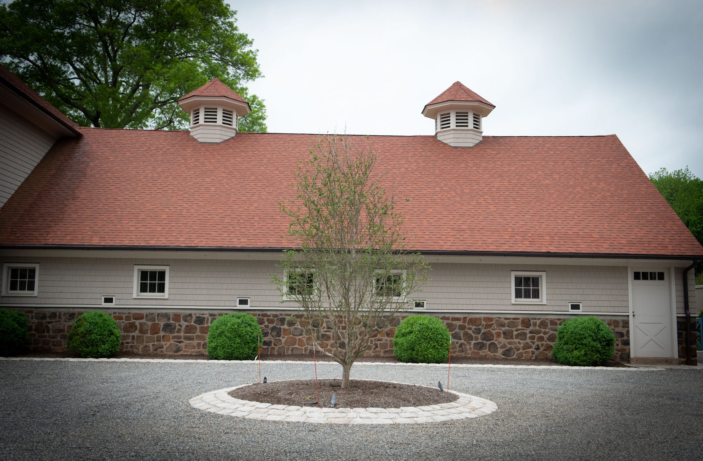 Rustic building with red roof and tree.