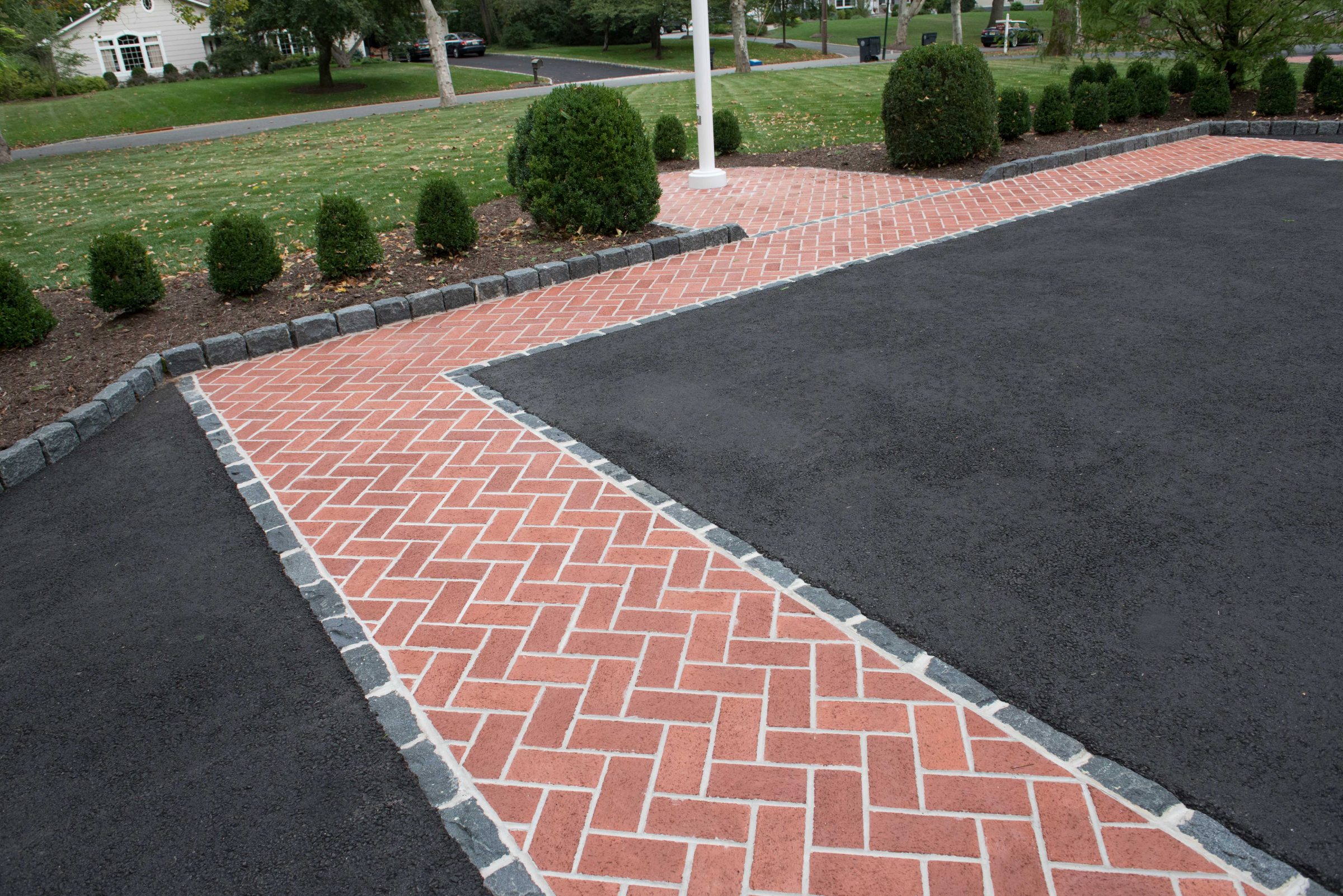 Brick and asphalt driveway with landscaping