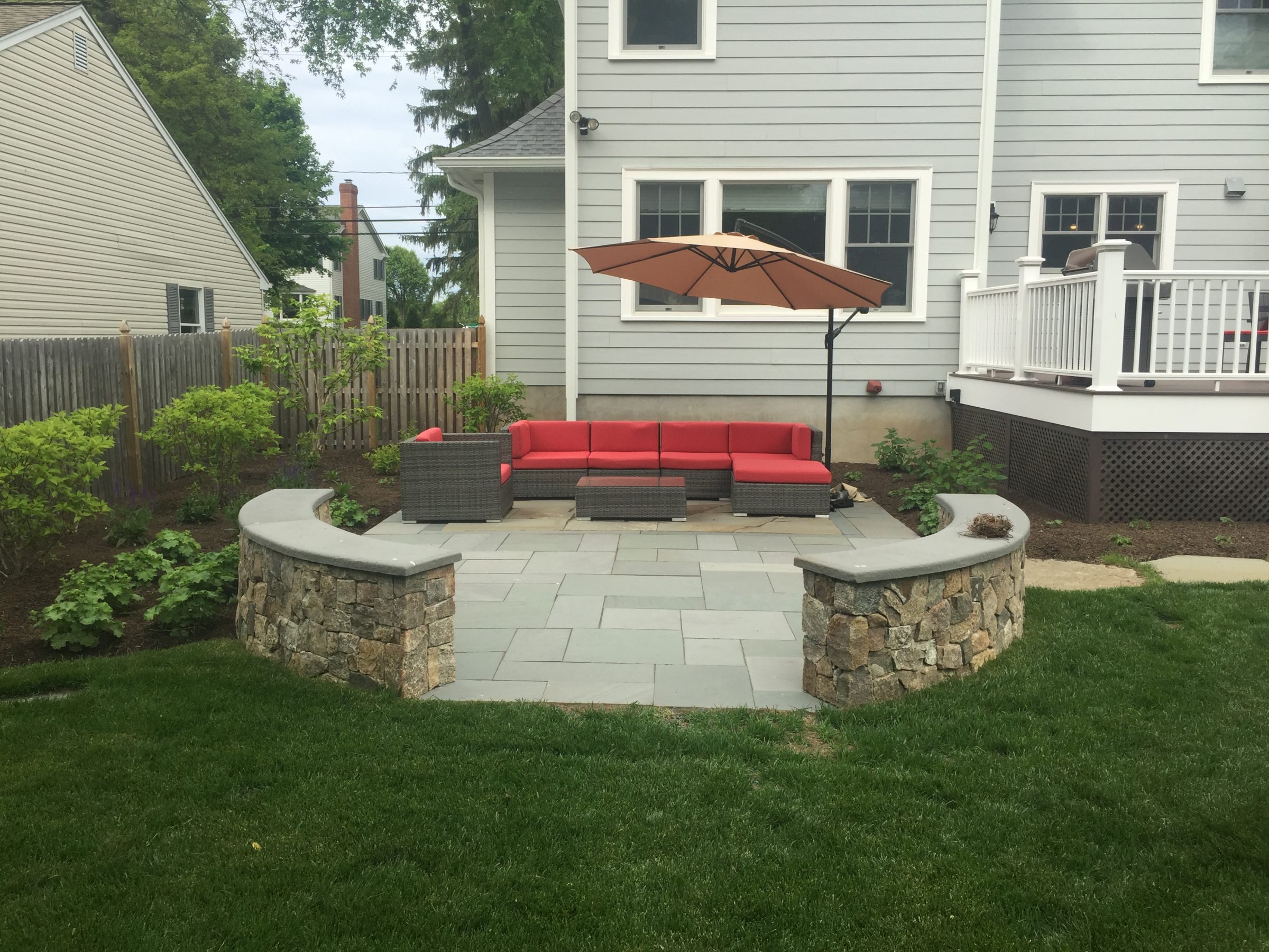 Backyard patio with red seating and umbrella