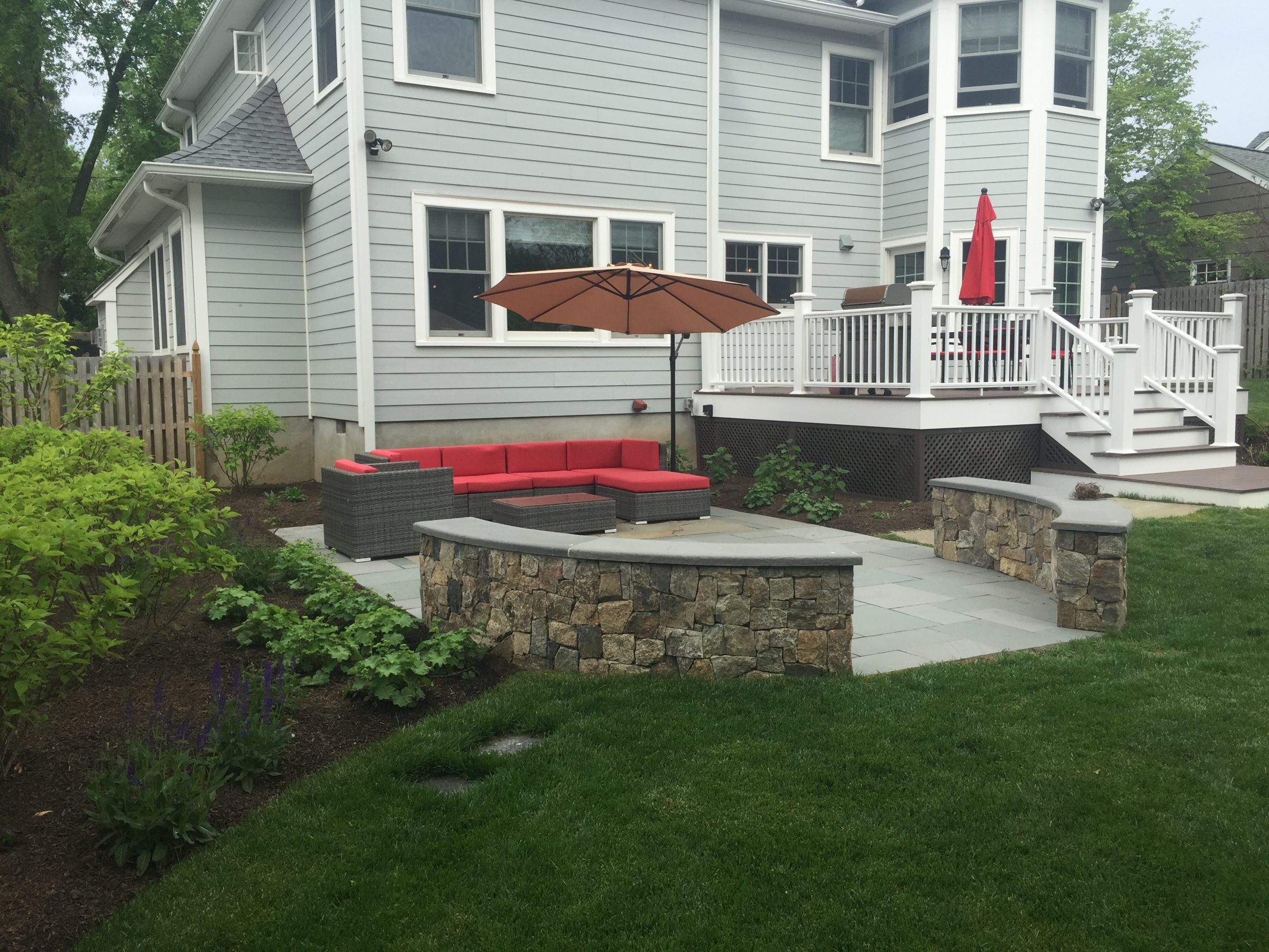 Backyard patio with red seating and umbrella