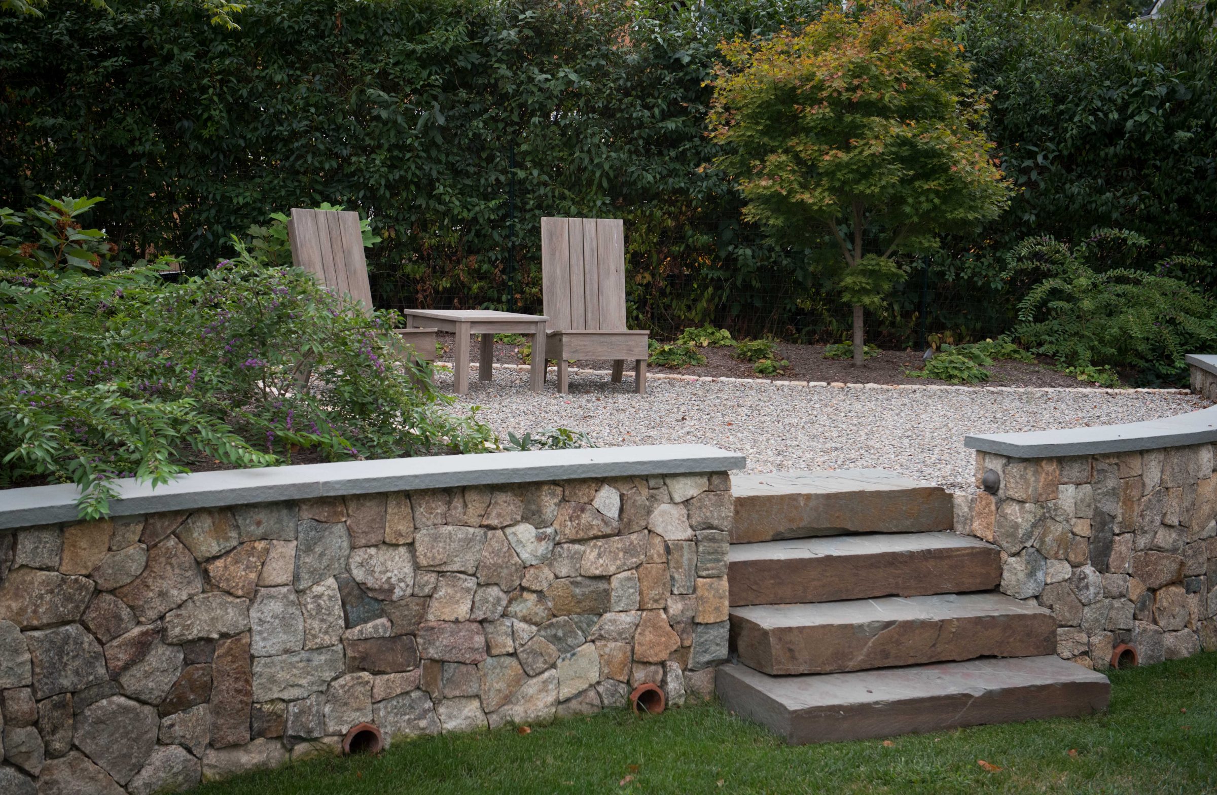 Outdoor stone patio with chairs and greenery