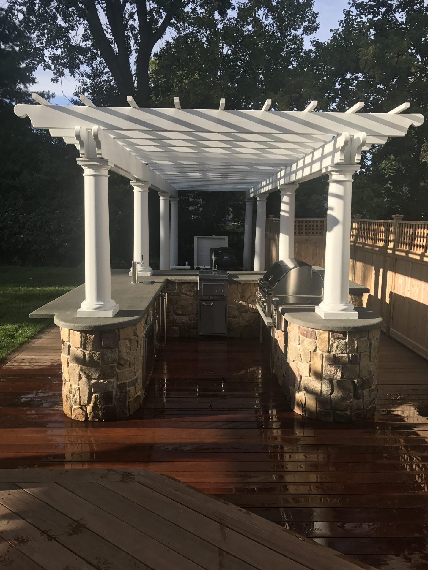 Outdoor kitchen with pergola on wooden deck.