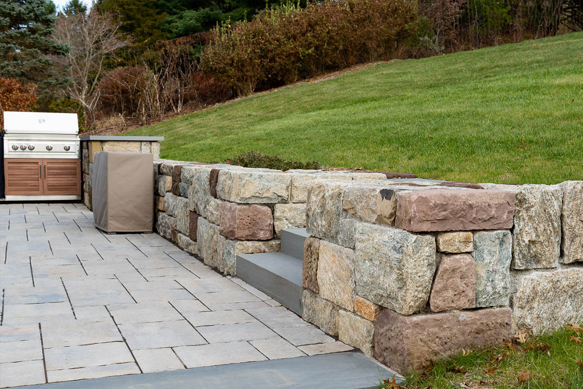 Outdoor patio with stone wall and grill