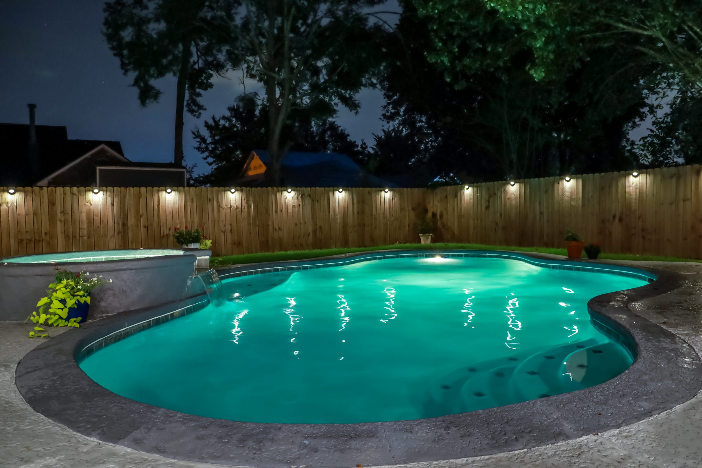 Illuminated backyard pool at night.