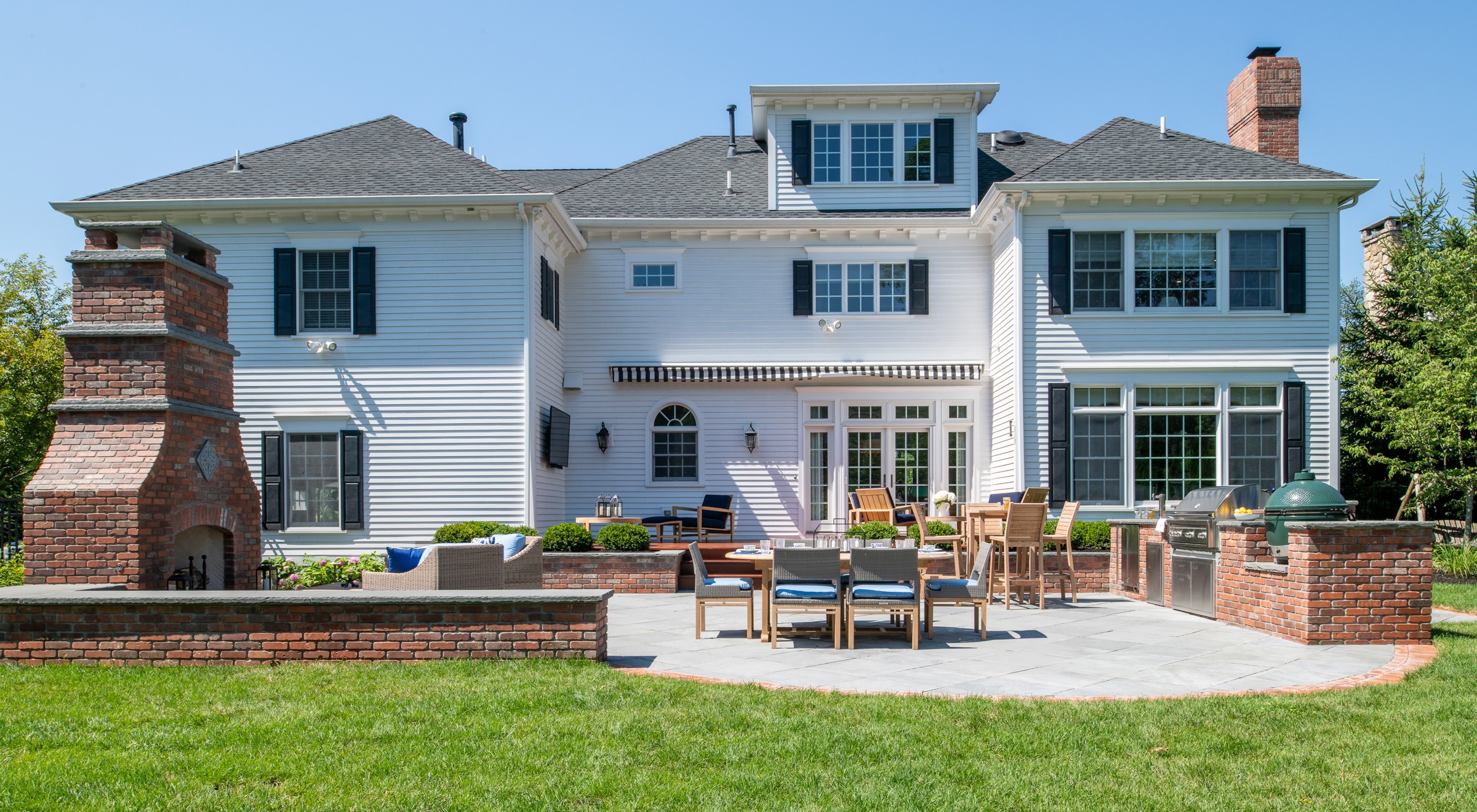 Large white house with brick patio and grill